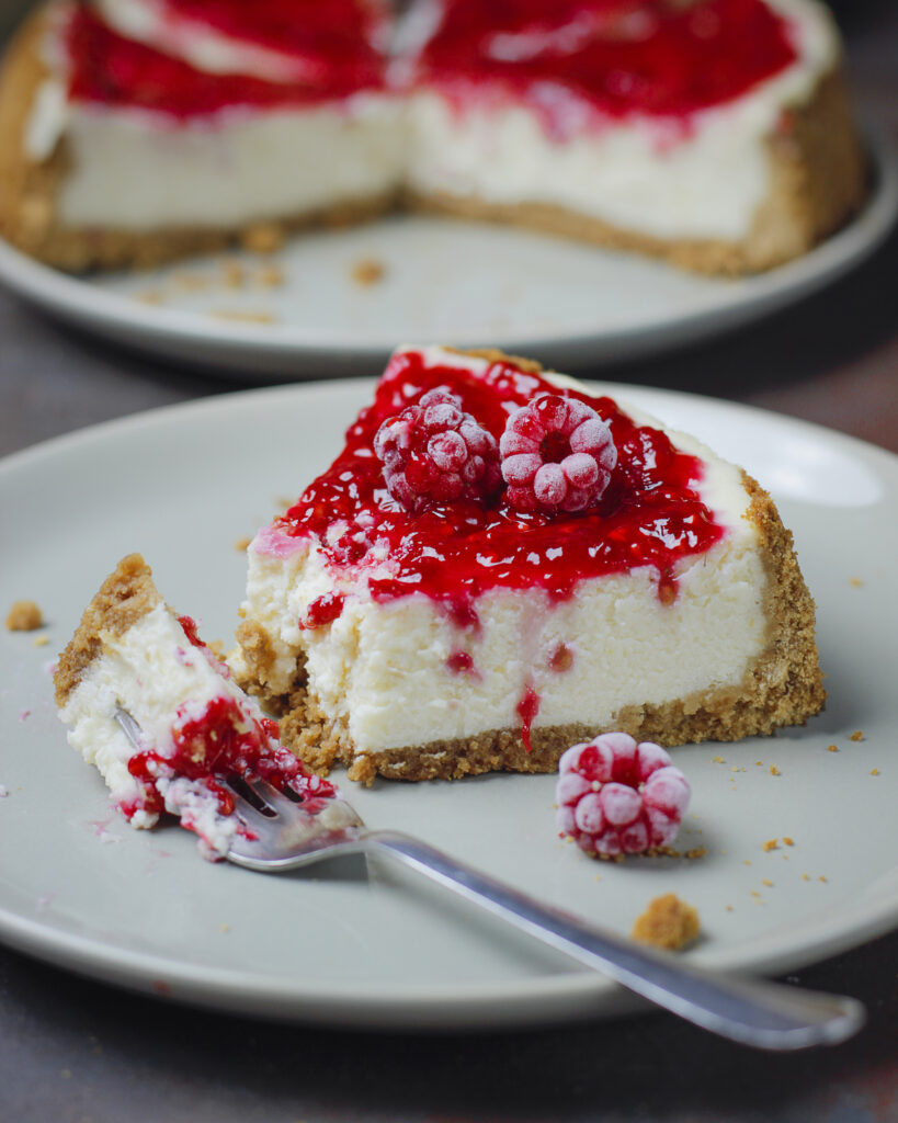 Cheesecake à la framboise dans une assiette avec deux framboises sur le dessus